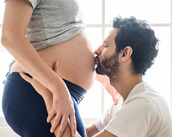 Fertilite-Fertility-Clinic-and-Reproductive-Medicine-in-Tijuana-San-Diego-Los-Angeles-In-Vitro-Fertilization-ICSI-IUI-IVF-PGTA-Gender-Selection-Young-Couple-Guy-Kissing-Girl-Pregnant-Belly
